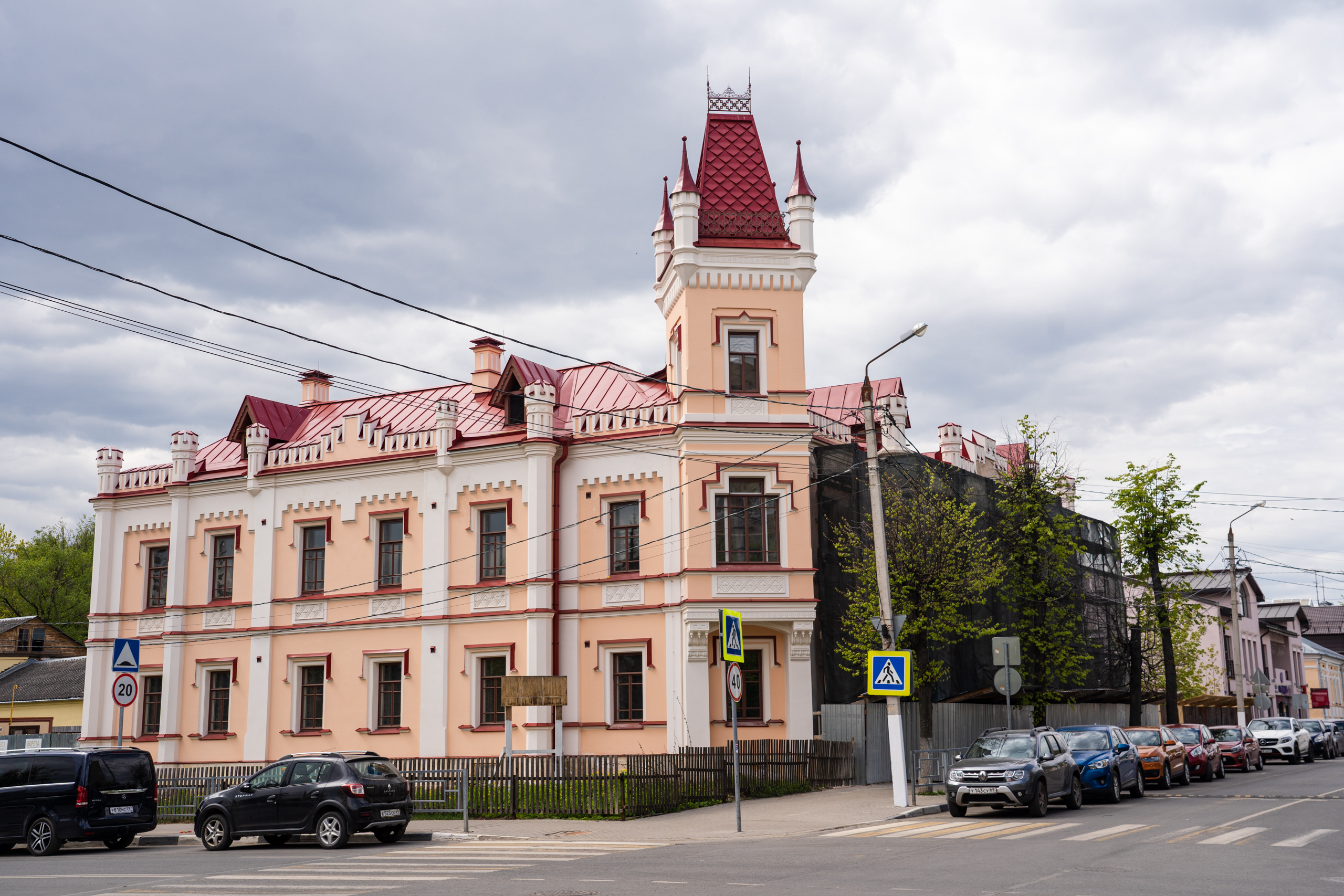 Экскурс в историю: Как в Твери устроили Аваевскую богадельню Особняк с красивой угловой башенкой, напоминающей если не виденное лично, то известное всем по фотографиям крымское «Ласточкино гнездо», входит в число уже устоявшейся десятки тверских достопримечательностей. Нам остается только согласиться с выбором – это здание действительно незаурядное, совсем недавно снаружи отреставрированное, и гордостью города является совершенно заслуженно. Многие знают, что его историческое название – «Аваевская богадальня». Василий Петрович Аваев (1811-1877) был одним из последних представителей тверского купечества старого типа. Потомок тверского купеческого рода. Аваев отметился и как благотворитель, и как общественный деятель: он постоянно избирался гласным (депутатом) городской думы, заседателем Уголовной палаты, попечителем ряда учебных и благотворительных заведений. Отмечен медалями, наградами, потомственным почетным гражданством. Здесь нужно отметить, что время, на которое пришлась его деятельность, было для губернской столицы трудным. В 1860-1870-х годах Тверь переживала период упадка. Старая транзитная торговля прекратилась, новая промышленность еще не поднялась. В городе был высокий процент бедного и даже нищего населения, на нужды которого постоянно обращал внимание Василий Петрович. Главным делом жизни Василия Аваева стало строительство и оснащение больницы, с предложением построить которую он обратился в городскую думу еще в 1874 году. Вплоть до своей смерти, уже больным, он не оставлял своего детища, лично проверял качество материалов, работ, следил за порядком на стройплощадке. Больница предназначалась преимущественно для православных жителей Твери, помощь оказывалась бесплатно, на что был оставлен капитал в 100 тысяч рублей и дополнительно капитал на стипендии для обучения студентов-медиков, будущих врачей этой больницы. Василий Петрович Аваев не дожил до окончания строительства. Больница была открыта 24 октября 1878 года, она стала лучшим на тот момент медицинским учреждением в городе. На средства Аваева значительная ежегодная помощь оказывалась и тверской публичной библиотеке, открытой в 1860 году. Василий Петрович оставил 2 тысячи рублей на то, чтобы городская публичная библиотека стала бесплатной. Что же касается богадельни, которая также была предметом его неусыпного внимания, то тут все вышло совсем не так просто, как хотелось бы. В декабре месяце 1881 года неспешно тянувшееся дело о постройке богадельни было передано было в «Подготовительную комиссию», а в ноябре 1882 года дума голосовала «о принятии мер к скорейшему приведению в исполнение воли жертвователя о постройке богадельни». В 1882 году второй душеприказчик Аваева, купец А.Е. Нечаев, обратился с новым заявлением в думу, прося сообщить «о причинах, по которым воля жертвователя не приводится в исполнение». Дума отреагировала: 2 ноября 1882 года она постановила комиссии по постройке здания богадельни все-таки отчитаться о проделанной работе, а архитектора Федорова 26 ноября 1882 года попросила как можно скорее составить план и смету на строительство. Между тем эти проблемы возникали отнюдь не вследствие отсутствия средств, а именно по причинам, с одной стороны, нерасторопности думы, а, с другой, загруженностью работой членов назначенной комиссии. Отчаявшись дождаться начала строительства, душеприказчики согласились на компромиссный вариант: город приобретает уже готовое здание, которое переоборудуется и превращается в богадельню. Вариант устраивал всех. Очень кстати подвернулось продаваемое на Секретарской (Пятницкой) улице доходное здание дворянки В. Копыловой, недавно построенное и вполне отвечавшее размерами и устройством тем требованиям, которые выдвигались к богадельне. За одним исключением: богадельня оказалась почти на центральной улице города, в дворянском квартале. Но с этим пришлось смириться. В 1884 году богадельня переехала в этот дом, настоящий дворец. Поэтому в Твери мы видим необычный факт: богадельня, располагавшаяся в подобных случаях в других городах на городских окраинах, в Твери соседствует с лучшими историческими гостиницами и дворянскими особняками. Впрочем, в наши дни бывшая богадельня вновь становится зданием с назначением, близким к первоначальному – это доходный дом. Богадельни в нем уже нет, да, наверное, и не имеет смысла размещать такие учреждения в здании, явно слишком маленьком и неудобном для современных учреждений общественного назначения. Но память о прошлом, о славном и честном тверском купце Василии Петровиче Аваеве, должна сохраняться в нем всегда.